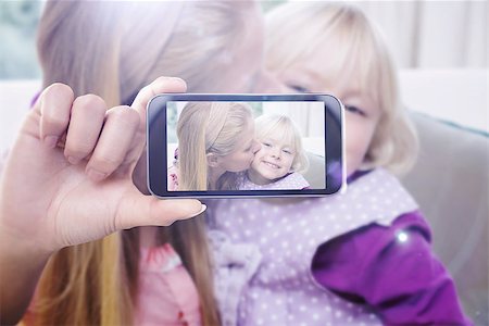 simsearch:400-07664794,k - Hand holding smartphone showing against happy mother and daughter on the couch Stock Photo - Budget Royalty-Free & Subscription, Code: 400-08076827