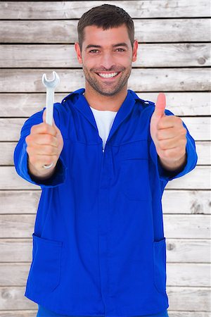 simsearch:400-08077202,k - Smiling mechanic holding spanner while gesturing thumbs up against digitally generated grey wooden planks Foto de stock - Super Valor sin royalties y Suscripción, Código: 400-08077189