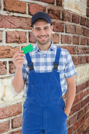 simsearch:400-08077176,k - Smiling young repairman holding green card against red brick wall Foto de stock - Super Valor sin royalties y Suscripción, Código: 400-08077193