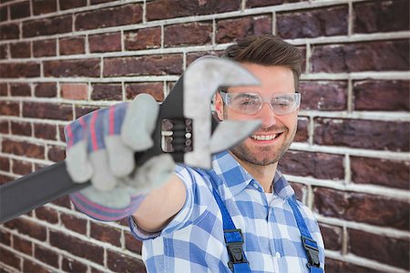 simsearch:400-08077176,k - Handyman wearing protective glasses while holding wrench against red brick wall Foto de stock - Super Valor sin royalties y Suscripción, Código: 400-08077229