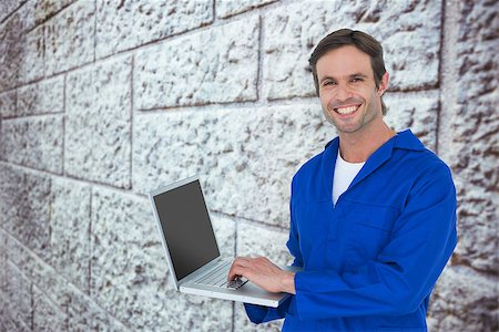 Handsome mechanic using laptop over white background against grey brick wall Stock Photo - Budget Royalty-Free & Subscription, Code: 400-08077249