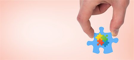 Hand holding jigsaw piece against orange Stock Photo - Budget Royalty-Free & Subscription, Code: 400-08077492