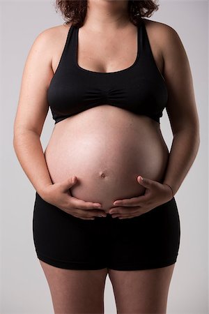 simsearch:400-04859723,k - Pregnant woman showing her belly, over a gray background Fotografie stock - Microstock e Abbonamento, Codice: 400-08070628