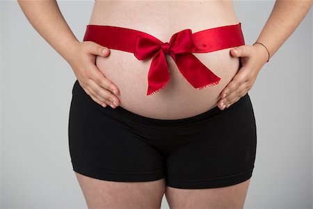 simsearch:400-08529613,k - Pregnant woman showing her beautiful belly with a red lace, over a gray background Stock Photo - Budget Royalty-Free & Subscription, Code: 400-08070630