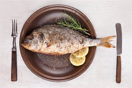 simsearch:400-07776969,k - Grilled fish with lemon and rosemary on brown plate with antique cutlery isolated on white wooden background with clipping path, top view. Mediterranean seafood background. Foto de stock - Super Valor sin royalties y Suscripción, Código: 400-08072045