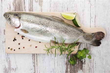 simsearch:400-07776969,k - Fresh trout with pepper corns, fresh herbs and lemon on wooden kitchen board on white wooden background ready for grill. Delicious grilling concept. Foto de stock - Super Valor sin royalties y Suscripción, Código: 400-08072049