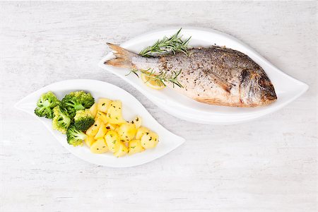 simsearch:400-07776969,k - Grilled gilthead bream with fresh rosemary herb, lemon and steamed potatoes and broccoli on white plate on white wooden background. Culinary bright seafood eating. Foto de stock - Super Valor sin royalties y Suscripción, Código: 400-08072040