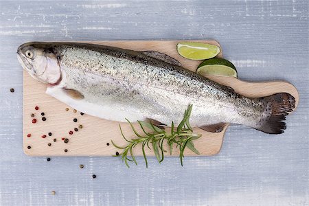 simsearch:400-07776969,k - Trout on wooden kitchen board with colorful peppercorn, fresh herbs and lime on blue wooden background. Culinary seafood eating. Foto de stock - Super Valor sin royalties y Suscripción, Código: 400-08072050