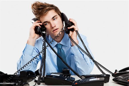 fünf sinne - Young man sitting in the office and answering several phones at the same time Photographie de stock - Aubaine LD & Abonnement, Code: 400-08072516