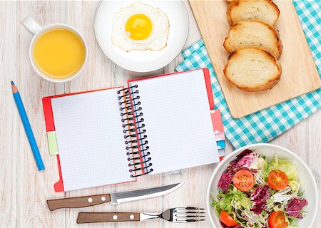 Healthy breakfast with fried egg, toasts and salad on white wooden table with notepad for copy space Stock Photo - Budget Royalty-Free & Subscription, Code: 400-08072804