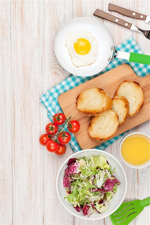 simsearch:400-06094801,k - Healthy breakfast with fried egg, toasts and salad on white wooden table. Top view with copy space Photographie de stock - Aubaine LD & Abonnement, Code: 400-08072803