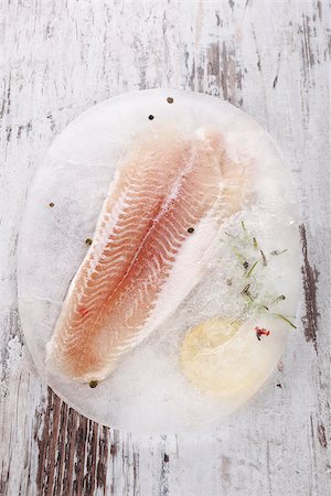 simsearch:400-08070549,k - Raw frozen fish fillet with fresh herbs and lemon on white wooden textured background. Culinary seafood eating. Stockbilder - Microstock & Abonnement, Bildnummer: 400-08073408