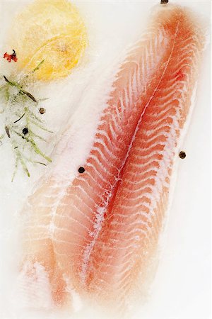 simsearch:400-08070549,k - Fish fillet frozen in ice with lemon, fresh herbs and peppercorns. Luxurious seafood eating. Stockbilder - Microstock & Abonnement, Bildnummer: 400-08073403