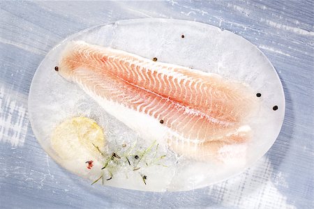 simsearch:400-08070549,k - Frozen pangasius fillet with fresh rosemary, lemon and peppercorns on blue wooden background. Culinary seafood eating. Stockbilder - Microstock & Abonnement, Bildnummer: 400-08073410