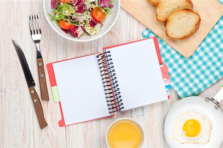 Healthy breakfast with fried egg, toasts and salad on white wooden table with notepad for copy space Stock Photo - Budget Royalty-Free & Subscription, Code: 400-08073880