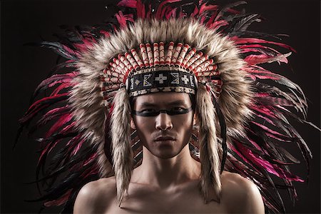 Portrait of the naked indian strong man posing with traditional native american make up  and headdress looking at the camera. Close up desaturated studio shot Stock Photo - Budget Royalty-Free & Subscription, Code: 400-08093442