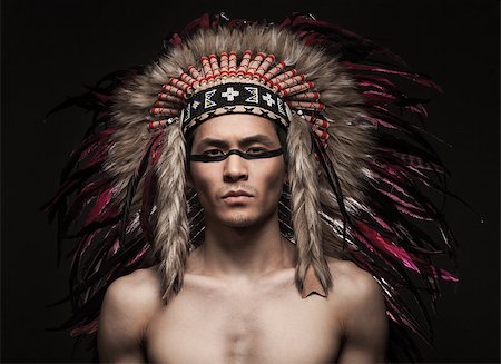 Portrait of the naked indian strong man posing with traditional native american make up  and headdress looking at the camera. Close up desaturated studio shot Stockbilder - Microstock & Abonnement, Bildnummer: 400-08093443