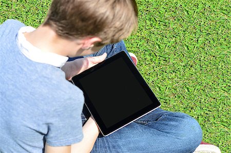 Boy sitting on lawn and using his new tablet pc Stock Photo - Budget Royalty-Free & Subscription, Code: 400-08108994