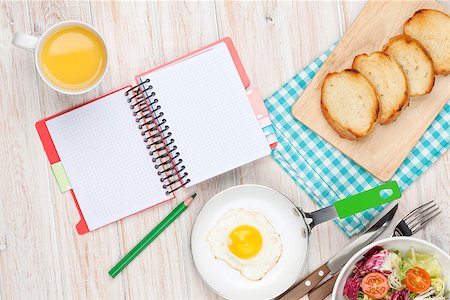 Healthy breakfast with fried egg, toasts and salad on white wooden table with notepad for copy space Stock Photo - Budget Royalty-Free & Subscription, Code: 400-08114336