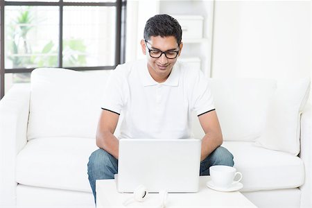 Young Indian guy start his new business with laptop computer from home. Asian man using internet indoor, relaxed and sitting on sofa. Handsome male model working indoors. Stock Photo - Budget Royalty-Free & Subscription, Code: 400-08114392