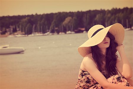 girl on beach , she is wearing floral dress hat , she enjoy the sun in the beautiful day.lake and boats in background.vintage color Stock Photo - Budget Royalty-Free & Subscription, Code: 400-08115606