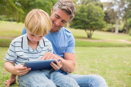 family with tablet in the park - Happy father with his son using tablet in the park on a sunny day Photographie de stock - Aubaine LD & Abonnement, Code: 400-08116245