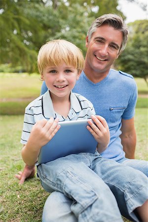 family with tablet in the park - Happy father with his son using tablet in the park on a sunny day Photographie de stock - Aubaine LD & Abonnement, Code: 400-08116246