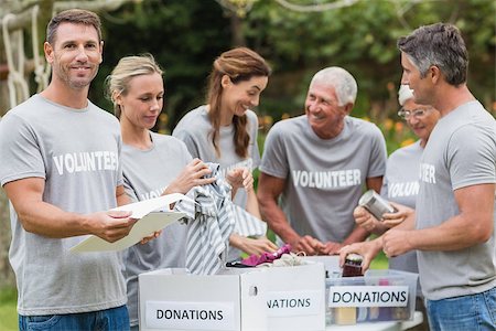 simsearch:400-08116305,k - Happy volunteer looking at donation box on a sunny day Stock Photo - Budget Royalty-Free & Subscription, Code: 400-08116380