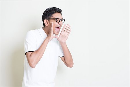Portrait of Indian guy shouting loud, mouth open and hand cupped beside. Asian man standing on plain background with shadow and copy space. Handsome male model. Stock Photo - Budget Royalty-Free & Subscription, Code: 400-08116549
