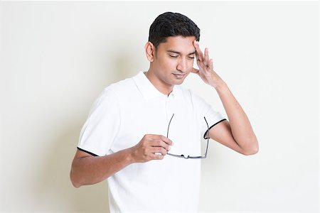 eyeglasses forehead - Portrait of tired Indian guy headache and massage his head. Asian man standing on plain background with shadow and copy space. Handsome male model. Photographie de stock - Aubaine LD & Abonnement, Code: 400-08116553