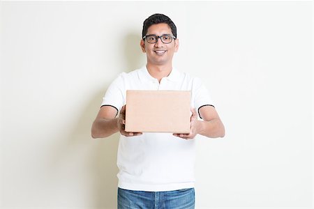 dispatch - Courier delivery service concept. Indian man sending a brown box, standing on plain background with shadow. Asian handsome guy model. Stock Photo - Budget Royalty-Free & Subscription, Code: 400-08116585