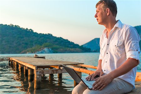man in a white shirt with a laptop on the pier to meet a dawn Stock Photo - Budget Royalty-Free & Subscription, Code: 400-08111296