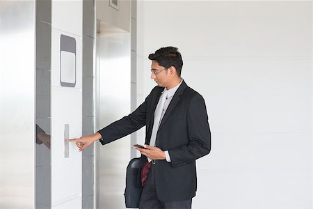 Asian Indian businessman pressing on elevator button, waiting door open to enter inside the lift. Stock Photo - Budget Royalty-Free & Subscription, Code: 400-08111355