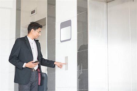 Young Indian businessman pressing on elevator button, waiting door open to enter inside the lift. Stock Photo - Budget Royalty-Free & Subscription, Code: 400-08111356