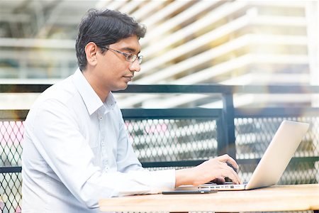 Candid Asian Indian businessman using laptop computer, modern building at background. Photographie de stock - Aubaine LD & Abonnement, Code: 400-08111377
