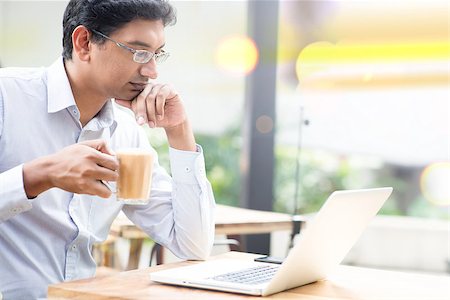 Man using laptop computer while drinking a cup hot milk tea, outdoor cafe. Photographie de stock - Aubaine LD & Abonnement, Code: 400-08111382