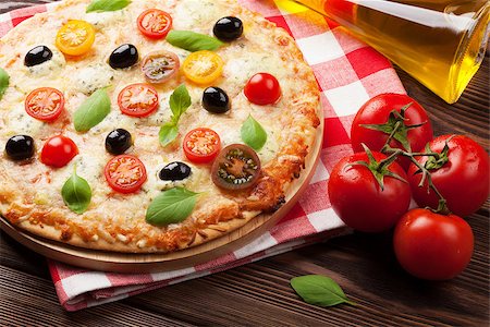simsearch:400-04539943,k - Italian pizza with cheese, tomatoes and basil on wooden table Stockbilder - Microstock & Abonnement, Bildnummer: 400-08111995