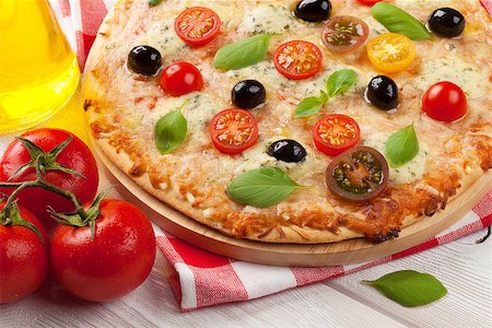 simsearch:400-04539943,k - Italian pizza with cheese, tomatoes and basil on wooden table Stockbilder - Microstock & Abonnement, Bildnummer: 400-08111997