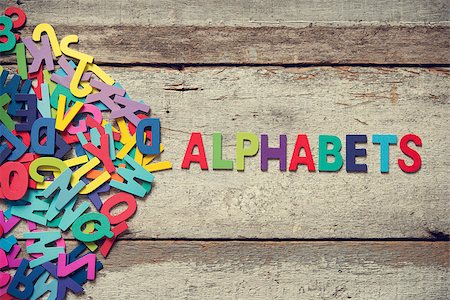 simsearch:400-07099266,k - The colorful words "ALPHABETS" made with wooden letters next to a pile of other letters over old wooden board. Fotografie stock - Microstock e Abbonamento, Codice: 400-08112250