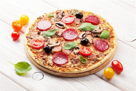 simsearch:400-04539943,k - Italian pizza with pepperoni, tomatoes, olives and basil on wooden table Stockbilder - Microstock & Abonnement, Bildnummer: 400-08112471