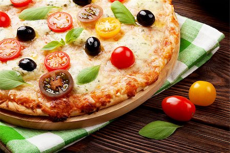 simsearch:400-05682309,k - Italian pizza with cheese, tomatoes, olives and basil on wooden table Stock Photo - Budget Royalty-Free & Subscription, Code: 400-08113663
