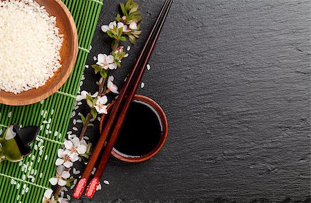 simsearch:400-07719212,k - Japanese sushi chopsticks over soy sauce bowl, rice and sakura blossom on black stone background. Top view with copy space Fotografie stock - Microstock e Abbonamento, Codice: 400-08113717