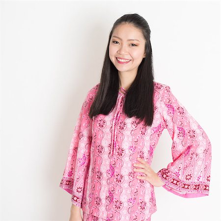 Portrait of happy Southeast Asian woman in pink batik dress standing on plain background. Stock Photo - Budget Royalty-Free & Subscription, Code: 400-08113758