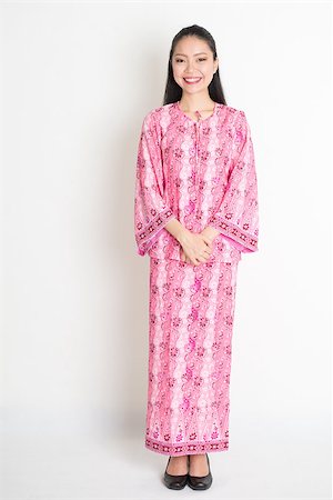 Full body portrait of happy Southeast Asian girl in pink batik dress standing on plain background. Stock Photo - Budget Royalty-Free & Subscription, Code: 400-08113759