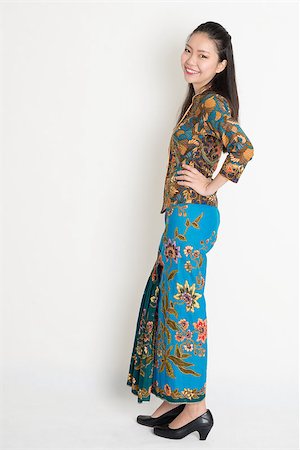 Full length cheerful Southeast Asian female in batik dress standing on plain background. Stock Photo - Budget Royalty-Free & Subscription, Code: 400-08113768