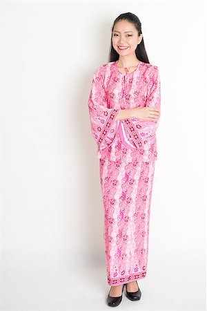 Full body portrait of happy Southeast Asian woman in pink batik dress standing on plain background. Stock Photo - Budget Royalty-Free & Subscription, Code: 400-08113761