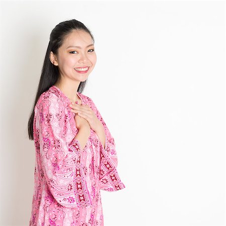 Portrait of happy Southeast Asian girl in pink batik dress standing on plain background. Stock Photo - Budget Royalty-Free & Subscription, Code: 400-08113762