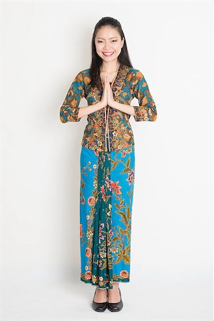 Full length Southeast Asian woman with batik dress in greeting gesture standing on plain background. Stock Photo - Budget Royalty-Free & Subscription, Code: 400-08113770