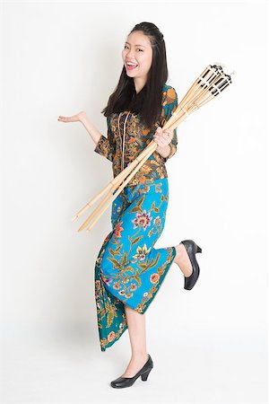 Full body portrait of happy Southeast Asian woman in batik dress hand holding bamboo oil lamp standing on plain background. Stock Photo - Budget Royalty-Free & Subscription, Code: 400-08113781