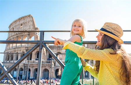 simsearch:400-08864986,k - A brunette mother wearing a hat in the summer in Rome is sitting next to her blonde, smiling daughter, and pointing. They are happy. In the distance, the Colosseum and crowds of summer tourists. Stock Photo - Budget Royalty-Free & Subscription, Code: 400-08134109